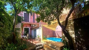 A backyard with a swimming pool, wooden deck, and potted plants. - The Sicilian (Acireale)