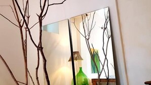 A room with a mirror reflecting a lamp and a green vase on a table. - The Sicilian (Acireale)
