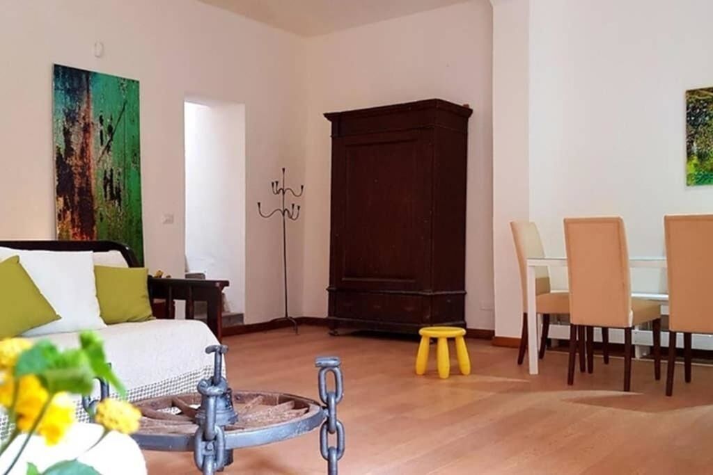 A room with a bed, a dining table with chairs, a wooden cabinet, and a painting on the wall.