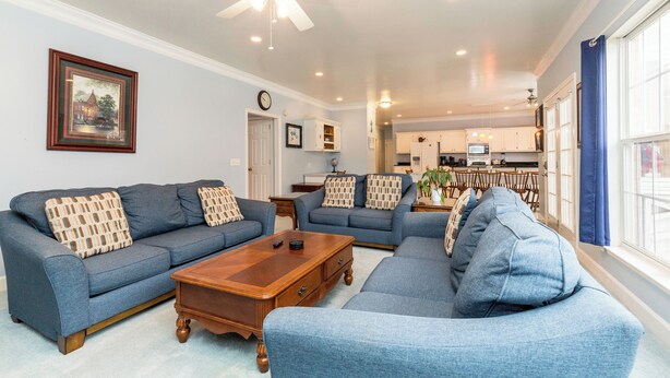 A living room with two sofas, a coffee table, and a ceiling fan.
