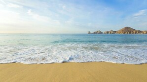 Une plage avec une eau d’un bleu limpide et un rivage sablonneux.