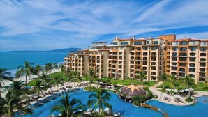 A hotel with multiple floors, a pool area, and a view of the ocean.