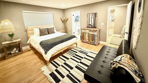 A modern bedroom with a large bed, a black sofa, a wooden floor, and a decorative rug. - The Ultimate Mountain Retreat - Yosemite, Bass Lake (Oakhurst)
