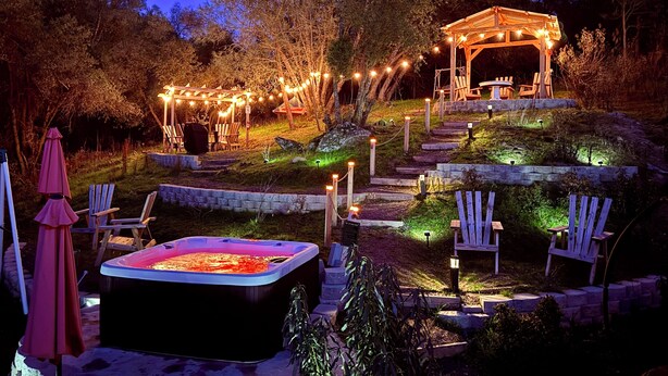 An outdoor patio area with a hot tub, wooden chairs, a gazebo, and string lights. - The Ultimate Mountain Retreat - Yosemite, Bass Lake (Oakhurst)
