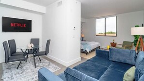 Een moderne woonkamer met een blauwe bank, een glazen salontafel en een televisie waarop 'NETFLIX' staat.