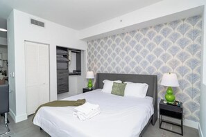A neatly arranged bedroom with a bed, two bedside tables with lamps, a wardrobe, and a mirror. - King Bed brand new safe Oasis minutes to Brickell (Miami)