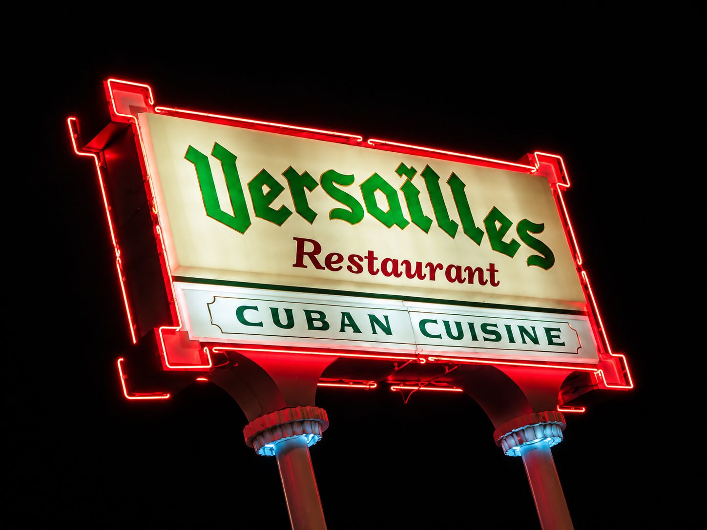 A neon sign for 'Versailles Restaurant' with 'Cuban Cuisine' written below.