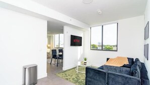 Ein modernes Wohnzimmer mit einem dunkelblauen Sofa, einem kleinen Couchtisch und einem an der Wand montierten Fernseher.