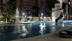 A swimming pool with a water fountain, lounge chairs, and a unique spiral water slide structure. - Apartment with direct access to the beach, fully equipped and renovated. (Acapulco de Juárez)