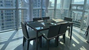 A dining area with a table and chairs, large windows, and a view of buildings. - Apartment with direct access to the beach, fully equipped and renovated. (Acapulco de Juárez)