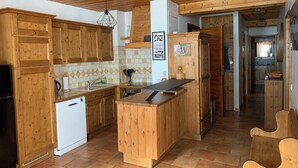 Une cuisine en bois dotée d’un îlot central, de meubles de rangement en bois et d’un lave-vaisselle blanc.