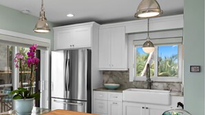 A modern kitchen with white cabinets, stainless steel appliances, a marble countertop, and pendant lighting. - Beautiful ocean front private beach 2-bedroom house gorgeous views Isla morada  (Islamorada)