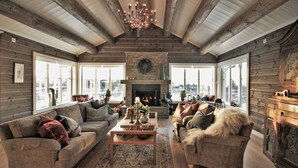 A cozy living room with a fireplace, wooden walls, and large windows offering a city view.