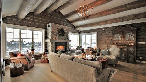 A cozy living room with a stone fireplace, leather sofas, and a chandelier.