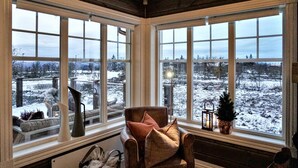 A cozy room with large windows offering a snowy landscape view.