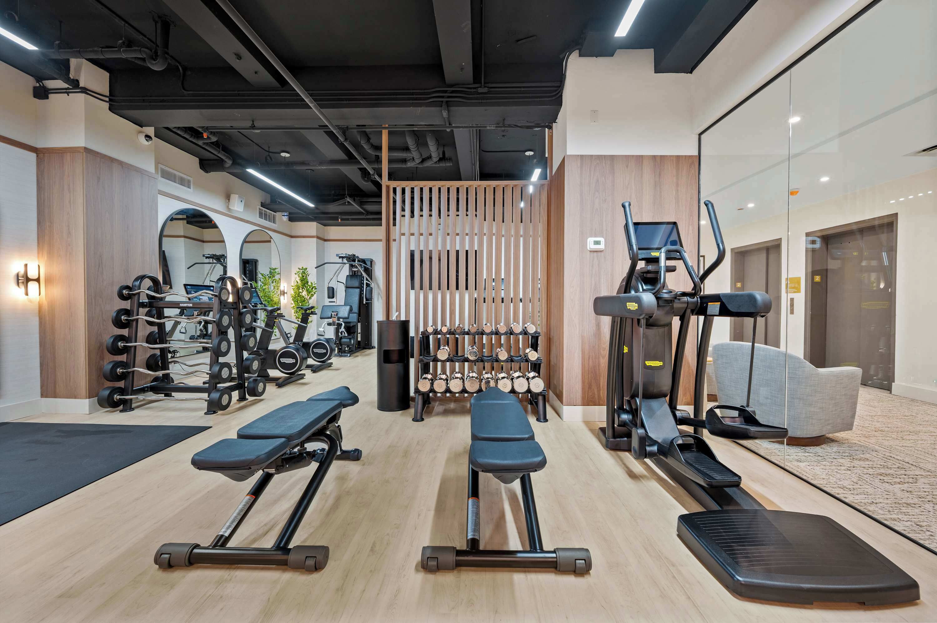 A gym with exercise equipment, benches, treadmills, and dumbbells.