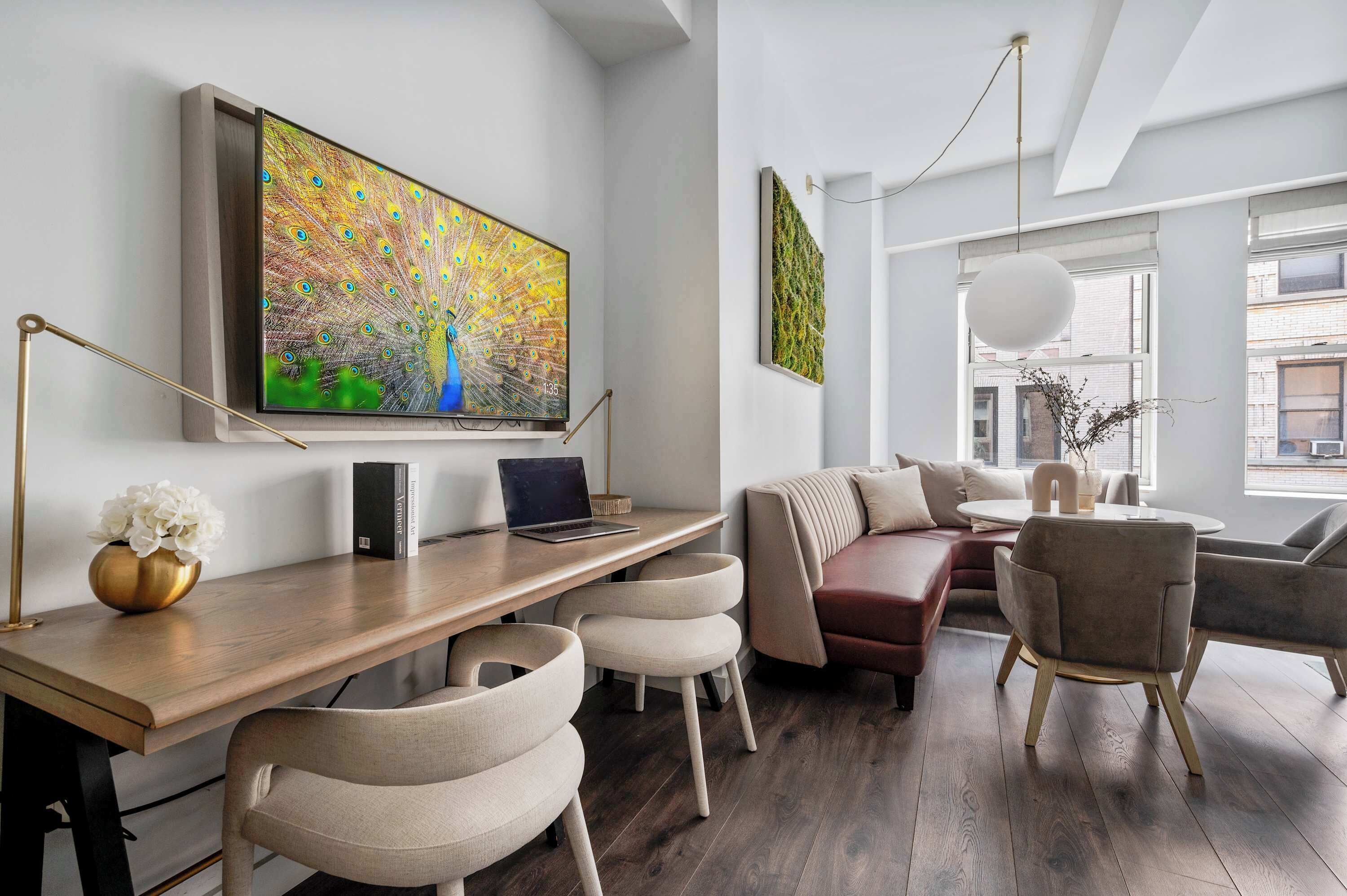 A modern living room with a wooden desk, a sofa, and a large painting of a peacock.