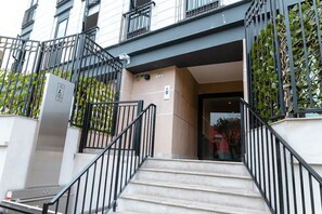 A building entrance with a staircase, a security box, and a number 391 sign.
