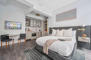Een moderne hotelkamer met een bed, nachtkastje en een klein zithoekje.