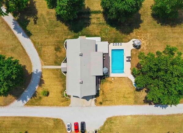 An aerial view of a house with a swimming pool, a driveway, and a road nearby. - Barndominium! Pool, HotTub, Slide, Mini B-Ball Court/Nerf Arena, Theater, 2 Bars (Terre Haute)