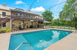 A poolside area with a covered patio, outdoor seating, and a pool. - Barndominium! Pool, HotTub, Slide, Mini B-Ball Court/Nerf Arena, Theater, 2 Bars (Terre Haute)