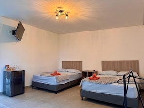 A hotel room with two beds, a TV mounted on the wall, and a ceiling light fixture.