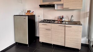 A compact kitchen with a refrigerator, a gas stove, and wooden cabinets. - CABIN WITH JACUZZI AND POOL PEÑOL GUATAPE  (Antioquia)