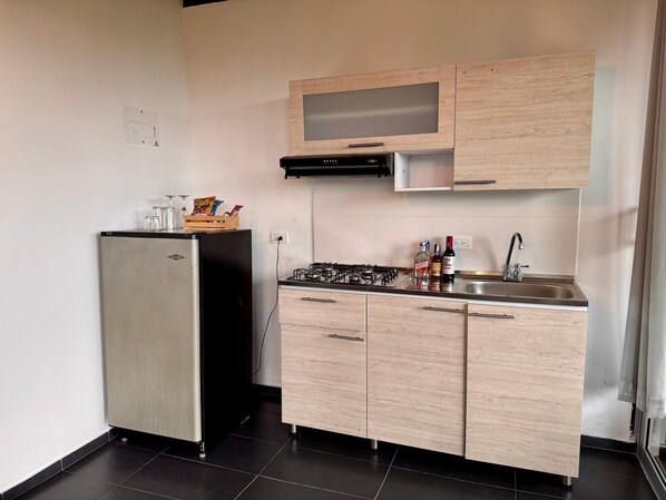 A compact kitchen with a refrigerator, a gas stove, and wooden cabinets.