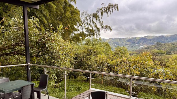 A balcony with a hot tub, outdoor seating, and a view of a mountainous landscape. - CABIN WITH JACUZZI AND POOL PEÑOL GUATAPE  (Antioquia)