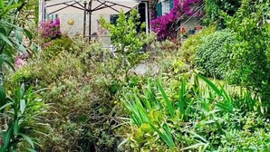 Um edifício de pedra com persianas verdes e uma área de estar coberta ao ar livre.