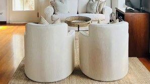Uma sala de estar com um sofá, uma mesa de centro e quadros na parede.