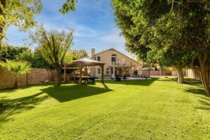 Relax in a serene outdoor space with a beautifully trimmed lawn and a charming pergola.