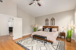 Relax in this serene bedroom with a large bed, decorative sconces, and a cozy bench.
