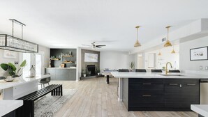 A modern kitchen with a central island, a dining area with a bench, and a fireplace. - Scottsdale Vacation Home Near Kierland|Heated Pool & Games (Scottsdale)