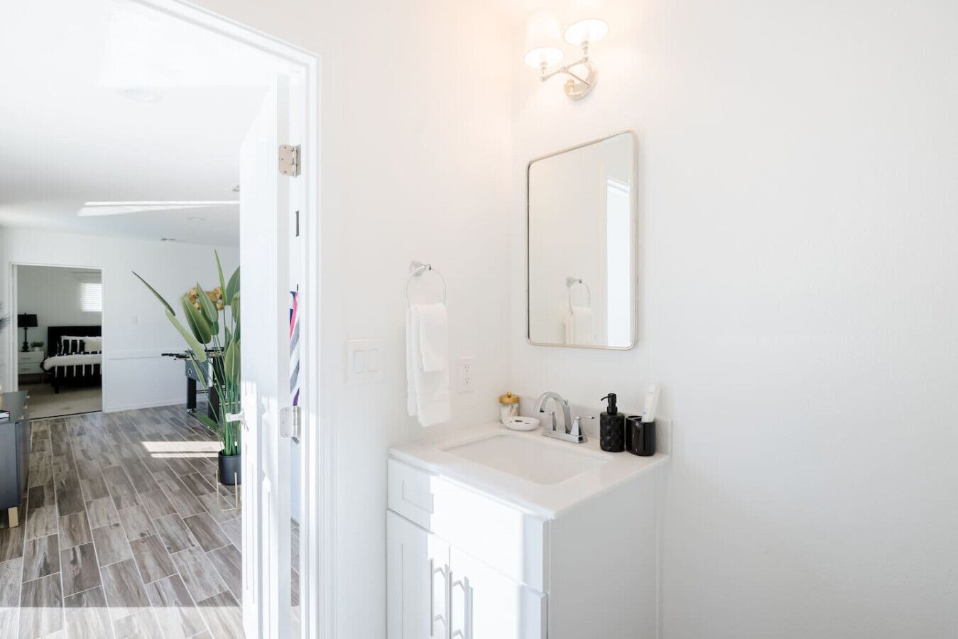 Un baño moderno con un lavamanos blanco, un espejo y un perchero para toallas.