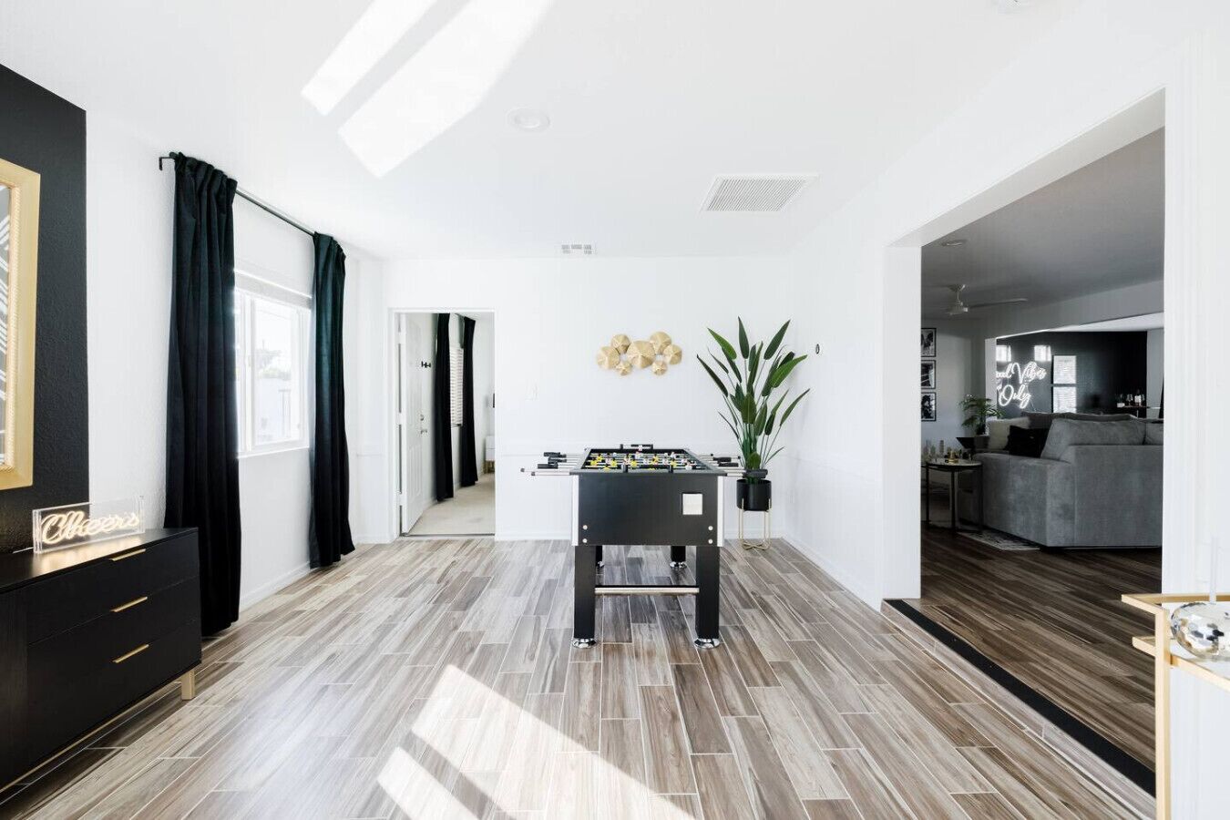 Un salon moderne avec un baby-foot, une plante en pot et un canapé.