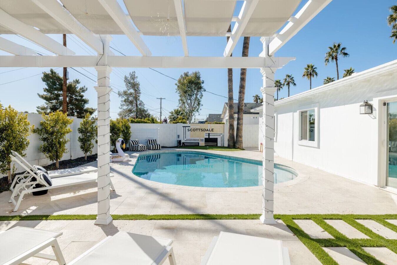 Un espace piscine agrémenté d’une pergola, de chaises longues et d’un panneau indiquant « SCOTTSDALE ».