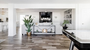 A modern living room with a central console table, a large potted plant, and a flat-screen TV mounted on the wall. - Best OldTown Scottsdale Location|Heated Pool|Spa (Scottsdale)