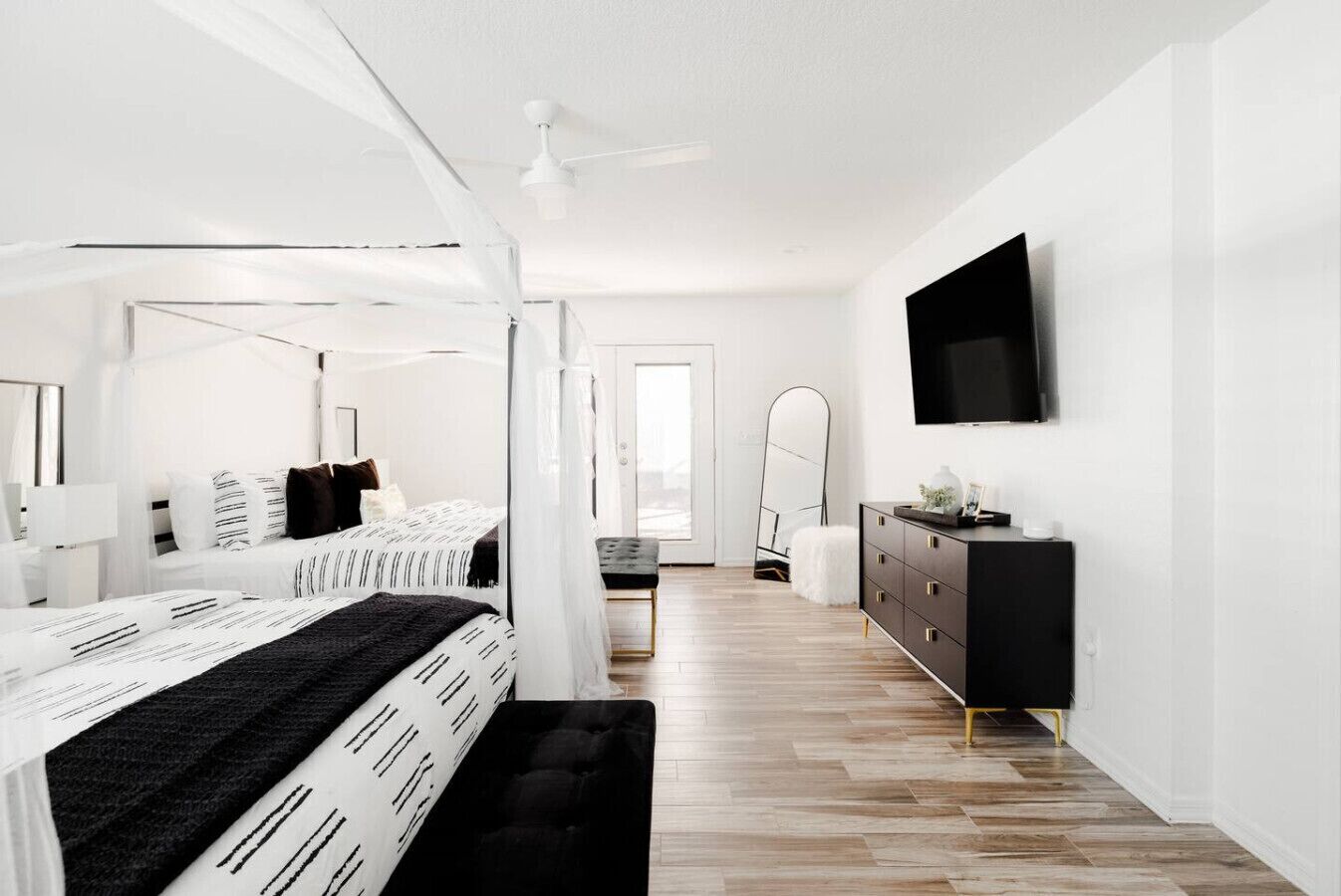 A modern bedroom with a bed, bedside table, dresser, and a TV on the wall.