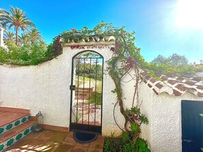 Traditional Spanish-style entrance with a wrought iron gate and lush greenery.