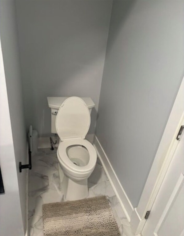 A small bathroom with a toilet, a white floor, and a door. - Newly Updated Buffalo Home Near Downtown (Buffalo)