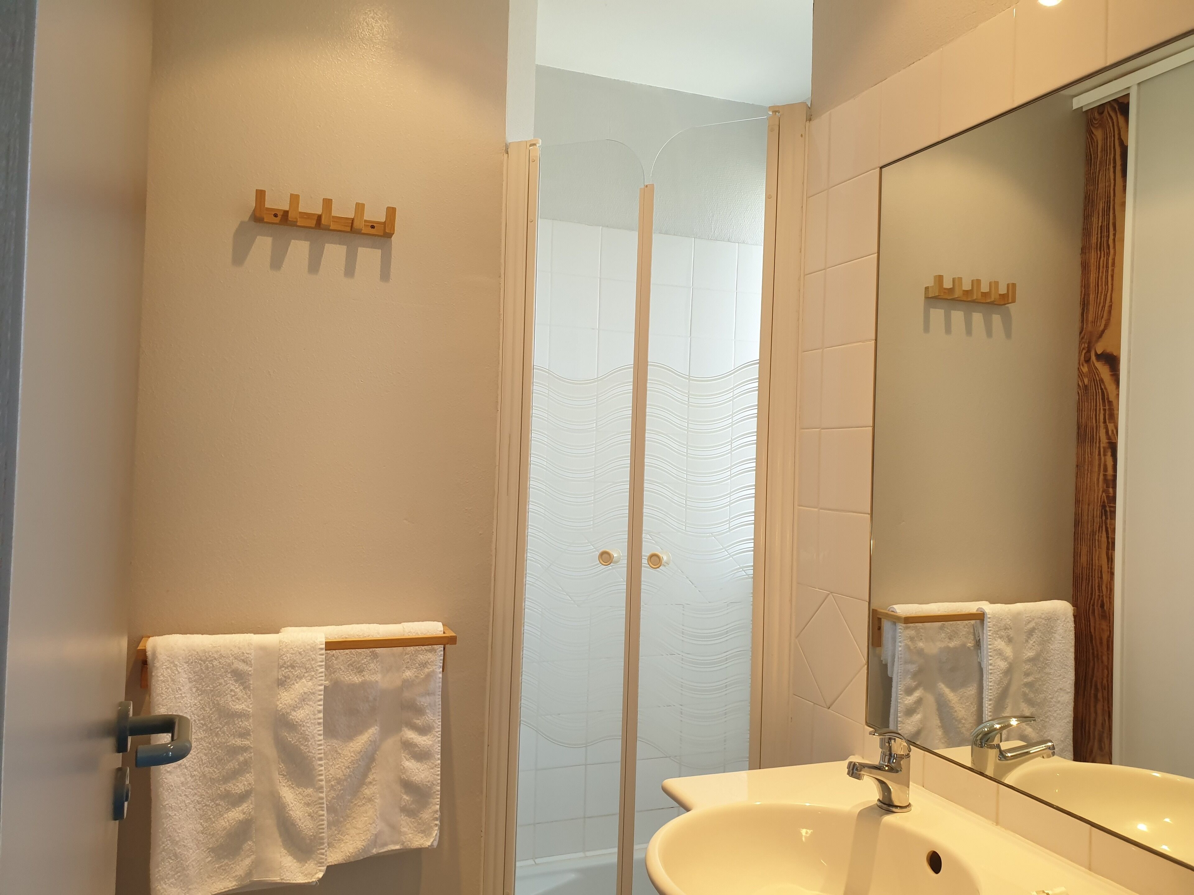 Een badkamer met een wit wastafelmeubel, een spiegel en een douche met ruitverdelende glazen deuren.