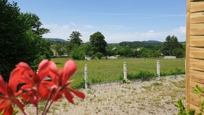 A rural landscape with a wooden fence, a gravel path, and a field in the background. - Auberge Bois de étang Motel les Tilleuls (Peyrat-le-Château)
