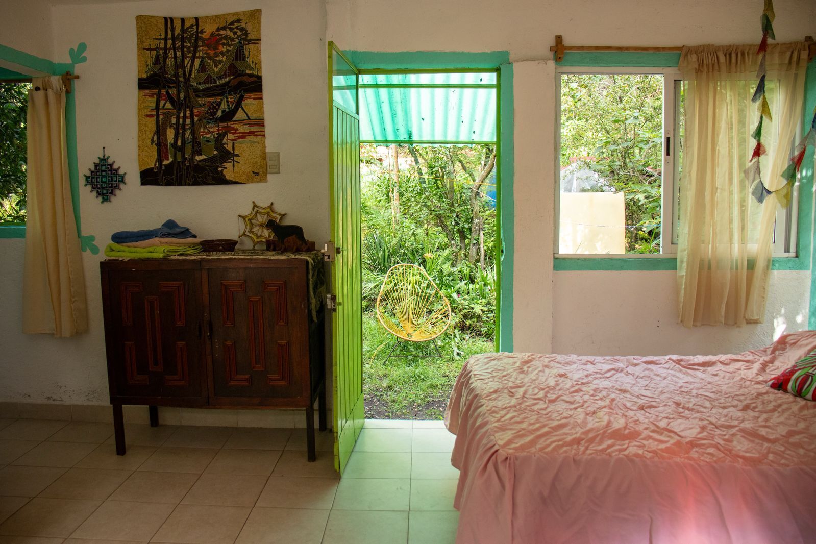 Un dormitorio con cama, armario, puerta que da a un jardín y un cuadro en la pared.