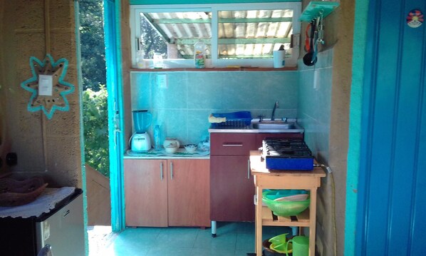 Una cocina compacta con ventana, un lavamanos, una estufa y una pequeña encimera.