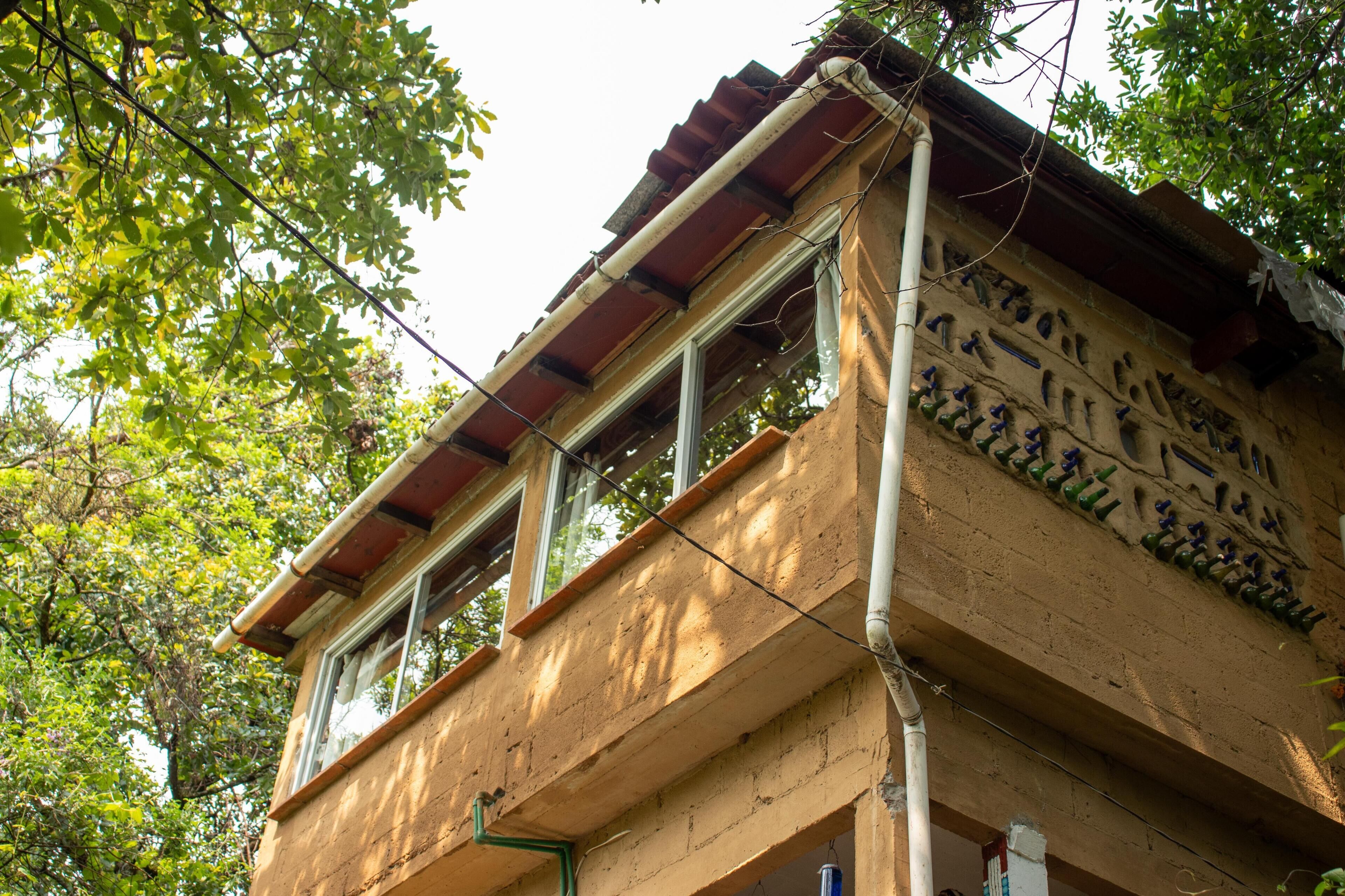 A building with a balcony, a window, and a tree in the background.