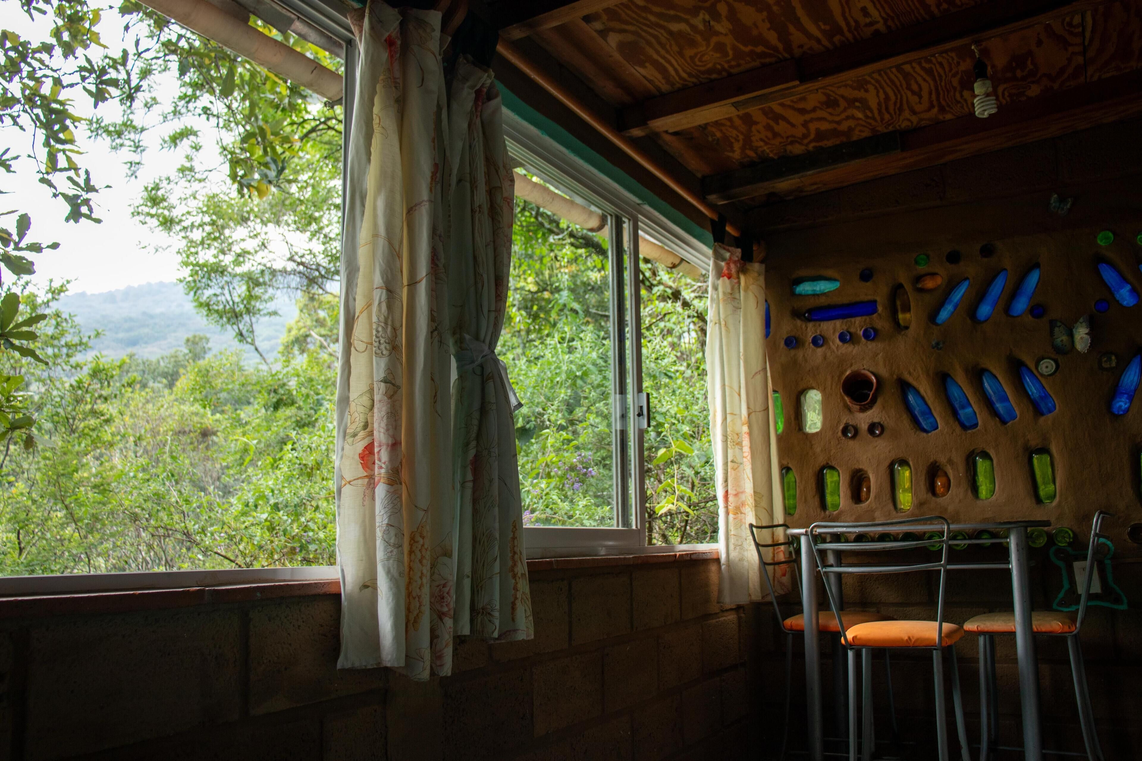 Una habitación con un ventanal grande, techo de madera y una pared decorada con formas de botellas.