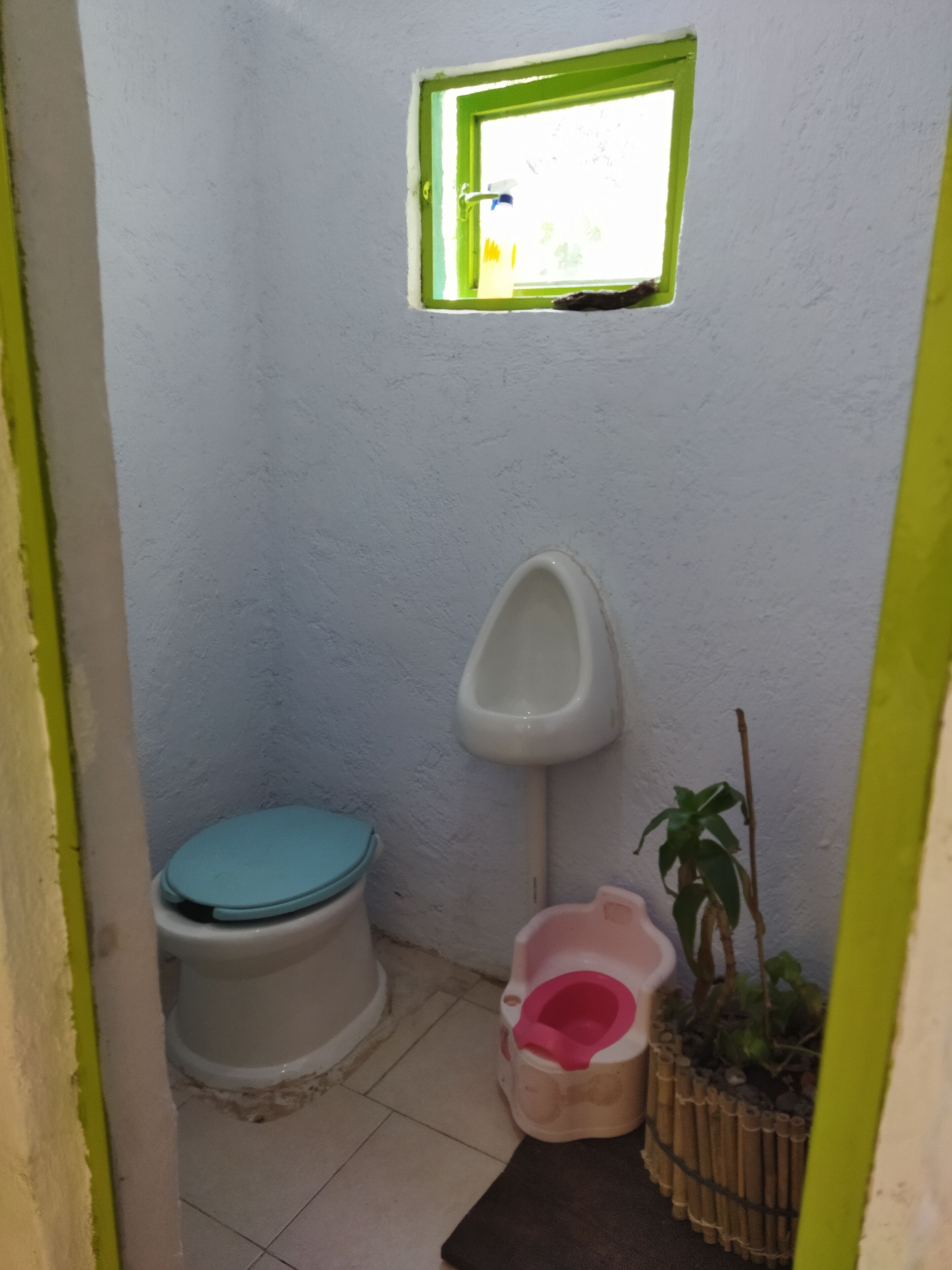 A small bathroom with a toilet, urinal, and a window.