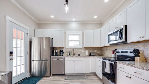 A modern kitchen with white cabinets, stainless steel appliances, and a granite countertop.