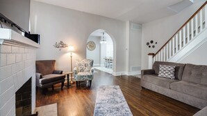 A living room with a fireplace, a sofa, a patterned armchair, and a rug.